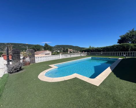 Piscine avec escaliers arrondi dans un jardin au gazon coupé à ras et un cile bleu sans nuages